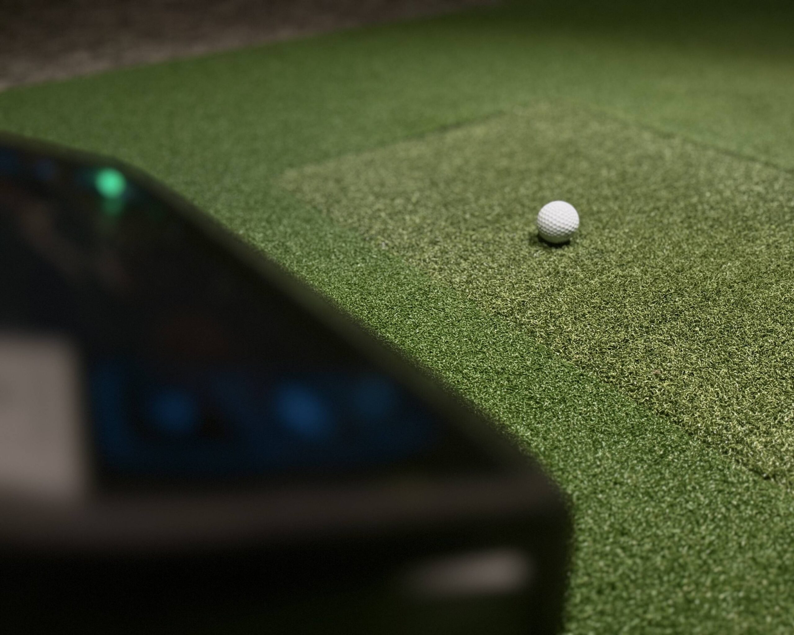 Golfball klar på utslagsmatten foran lerretet